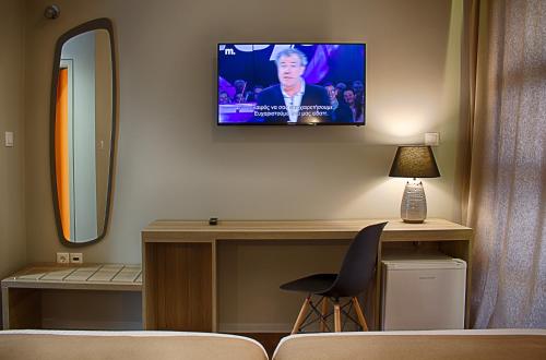 塞萨洛尼基Athlos Hotel的一间房间,墙上配有电视和椅子
