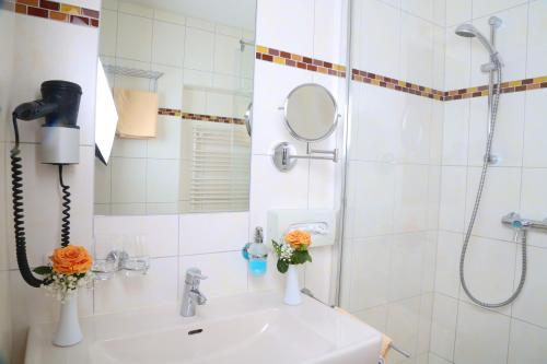 格蒙登恩格尔霍夫旅馆的浴室配有淋浴和鲜花水槽。
