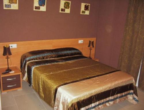 Higuera de LlerenaHostal el mirador的一间卧室配有一张床和两盏灯,墙上挂着图片