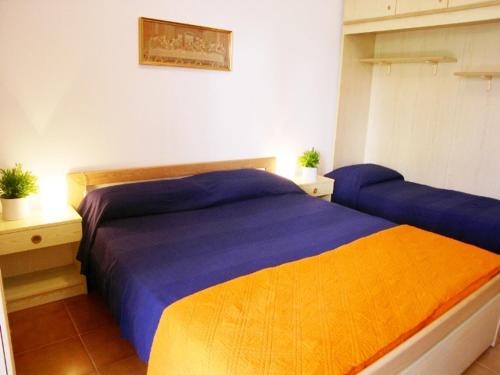 格拉多Condominio Alto Adriatico的一间在客房内配有蓝色和橙色床的卧室