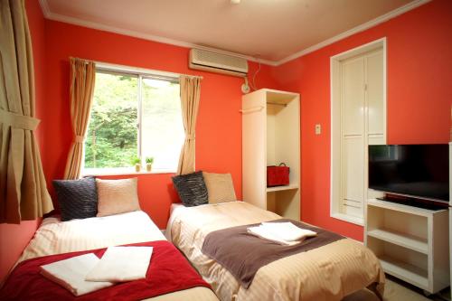 轻井泽轻井泽佐藤奴库利旅馆的红色墙壁客房的两张床
