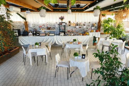 那不勒斯Hotel Residence Confalone的一间设有白色桌椅的餐厅以及一间自助餐