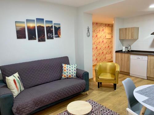 贝纳斯克Apartamentos Maladeta的一间带紫色沙发的客厅和一间厨房