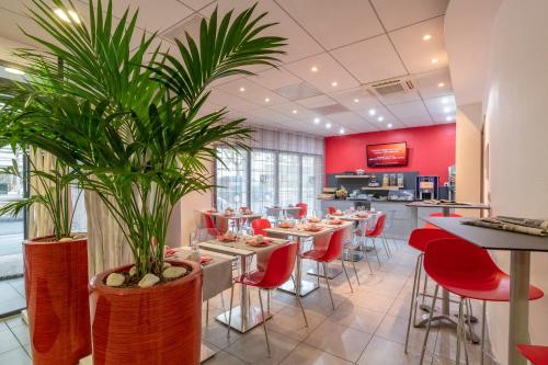 拉罗谢尔Lagrange Apart'Hotel l’Escale Marine的一间设有桌子和红色椅子的餐厅,种植了植物