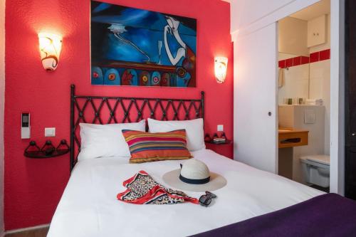 戛纳布里默戛纳酒店的红色卧室,配有带帽子的床