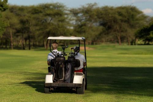 阿鲁沙Kili Villa Kilimanjaro Luxury Retreat的两个在高尔夫球场高尔夫球车上的人