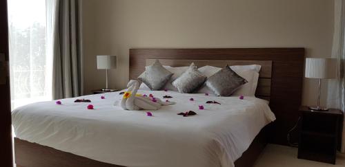 蒙舒瓦西Northern Pearl Luxury Apartments的卧室配有带玫瑰花的白色床