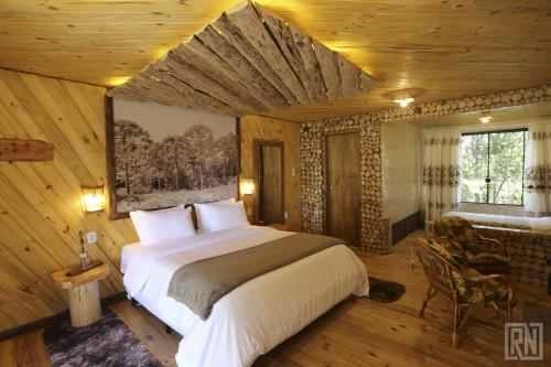 圣若阿金Pousada Serra Catarinense的木制客房内的一间卧室配有一张大床