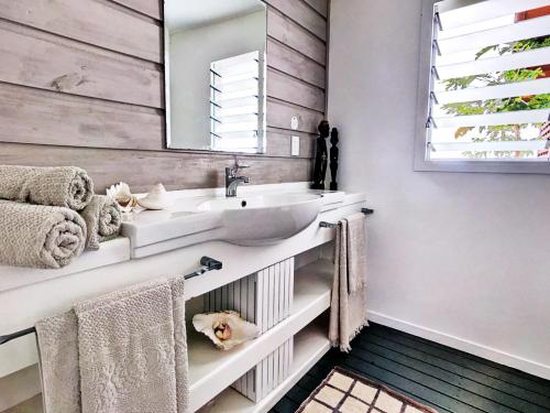 卢甘维尔Sails Beach House的浴室配有盥洗盆、镜子和毛巾