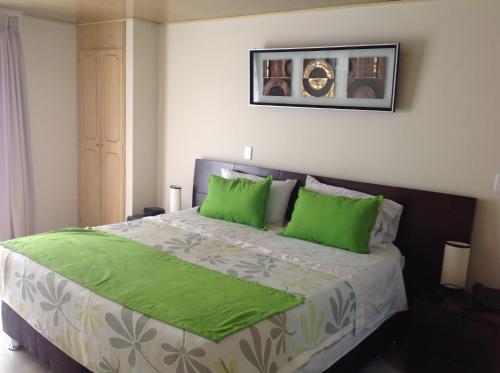 波哥大Hoteles Bogotá Inn El Lago Country的一间卧室配有一张带绿色枕头的大床