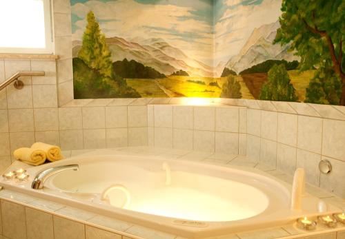 Grafling巴伐利亚森林酒店的带浴缸的浴室,墙上有绘画作品