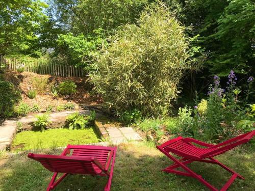 Saint-Quay-PerrosManoir des petites bretonnes的花园里的草地上摆放着两把红色的椅子
