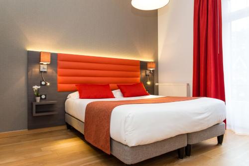 拉波勒鲁特蒂亚Spa酒店的一间卧室配有一张带橙色床头板的大床