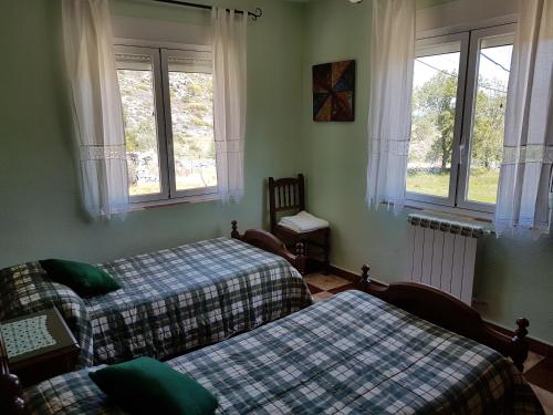 Navalguijo拉斯科雷拉斯乡村民宿的一间卧室设有两张床、一张沙发和窗户。