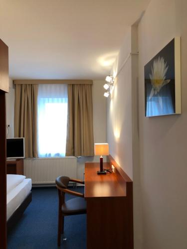 埃朗根Hotel Mirabell的酒店客房配有一张床和一张带台灯的书桌