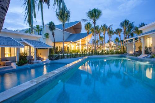普吉镇CRAFT Resort & Villas, Phuket Town的棕榈树屋前的游泳池