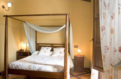 奥利瓦Hotel Restaurante Font Salada的一间卧室配有一张带2个床头柜和2盏灯的天蓬床。