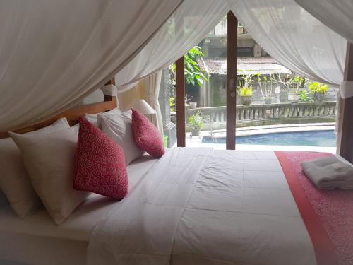 乌布拉卡旅馆的一间卧室配有红色和白色枕头的床
