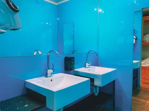 波尔图CATS Porto Hostel的蓝色的浴室设有两个盥洗盆和镜子