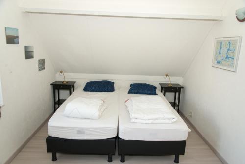 布雷斯肯斯Hello Zeeland - Vakantiehuis Zwin 218的小房间设有两张床,配有两张边桌