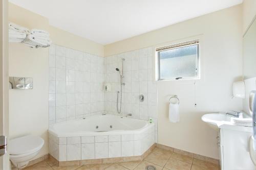 阿希帕拉Ahipara Bay Motel的白色的浴室设有浴缸和卫生间。