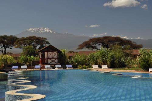 安博塞利乞力马旅行者帐蓬式酒店的一个带椅子的游泳池,后方是一座山。