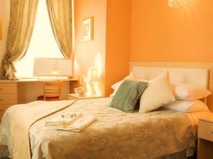 索恩The Punchbowl Inn的一间卧室配有一张带橙色墙壁和窗户的床