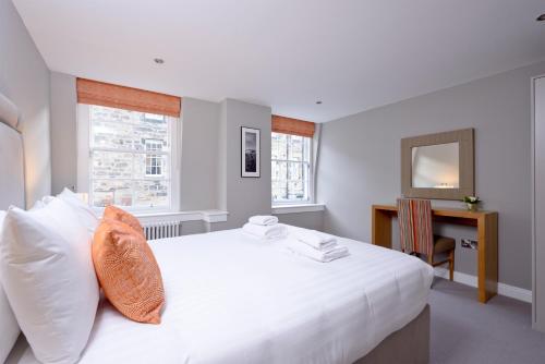 爱丁堡Destiny Scotland New Town Apartments的白色卧室配有一张大白色床和橙色枕头