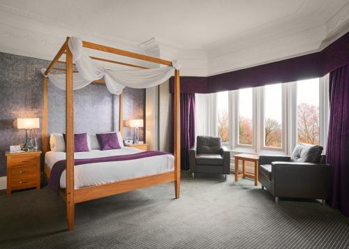 帕迪厄姆Burnley West Higher Trapp Hotel的一间卧室配有一张天蓬床和一把椅子