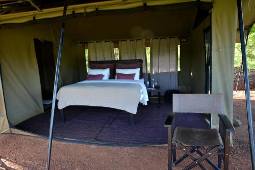 NaboishoBasecamp Wilderness的帐篷内的卧室,配有一张床和椅子
