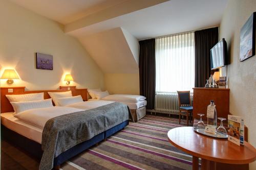 杜塞尔多夫Sure Hotel by Best Western Ambassador Duesseldorf的酒店客房设有两张床和一张桌子。
