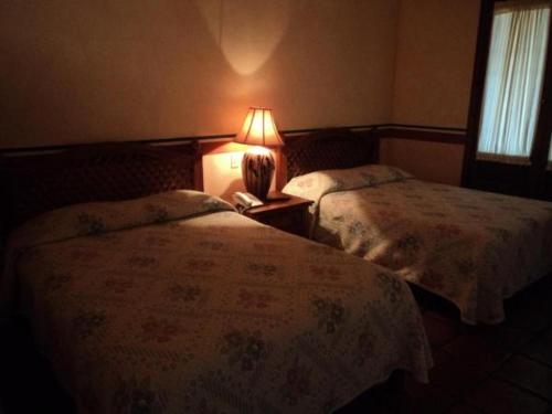 纳沃华Hotel Hacienda Cazadores的一间卧室配有两张床和床头灯。