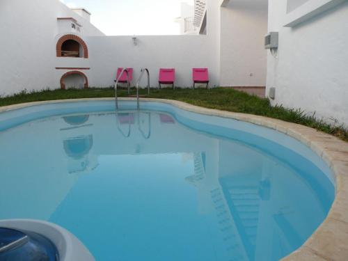 拉腊什Villa El Andalousse的一座游泳池旁设有两把粉红色椅子