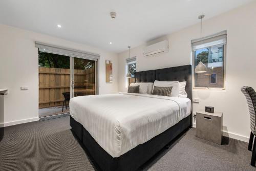 墨尔本Melbourne Airport Motel的一间带大床的卧室和一个阳台