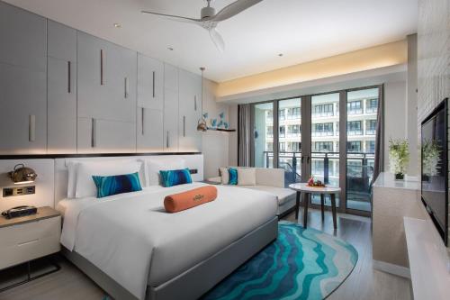 三亚三亚金都蔚景温德姆酒店（大东海）的卧室配有一张白色的大床和一张沙发。