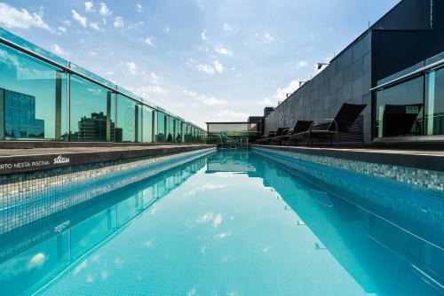 阿雷格里港Hotel Laghetto Moinhos的一座大型游泳池,设有玻璃窗户,位于大楼内