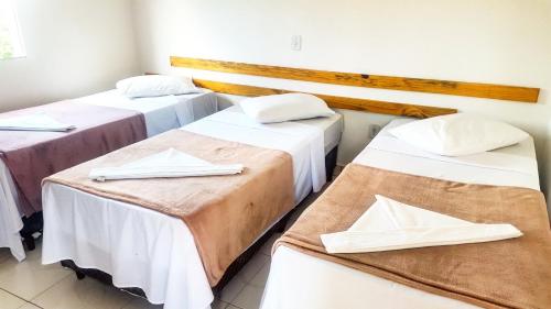 塞拉内格拉Chalé Alto da Serra SP的配有白色床单和餐巾的客房内的三张床