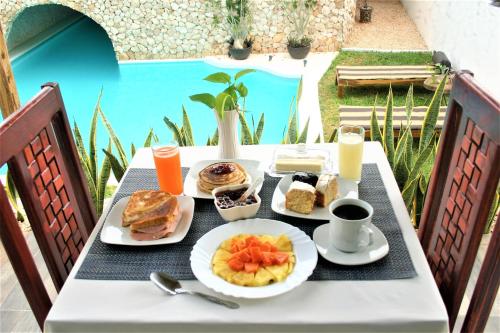 巴利亚多利德Mayan Majesty Boutique Hotel的一张桌子,上面有早餐食品,还有游泳池