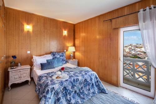 阿尔布费拉Sea View Downtown - Albufeira的一间卧室配有一张带蓝色毯子的床和窗户。