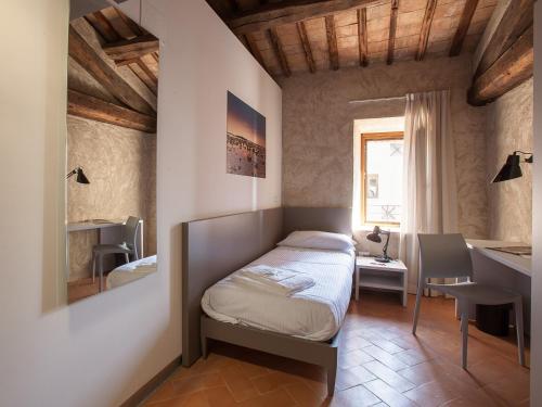 桑塔斯维尔Ostello del Castello di Santa Severa的一间卧室配有一张床、一张书桌和一个窗户。