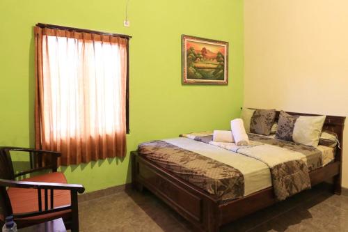 金巴兰Kubu Turah Homestay的一间卧室设有一张带绿色墙壁和窗户的床。
