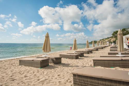 克兰内沃Effect Algara Beach Resort - Ultra All Inclusive and Free Parking的海滩上的一排遮阳伞和椅子