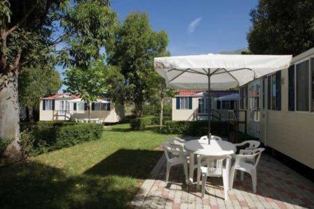 马拉泰亚Villaggio Camping Maratea的庭院配有桌椅和遮阳伞。
