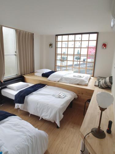 名古屋駐車場無料 Nagoya Hostel The Three Smiles Free Car Park的带三张床和两扇窗户的房间