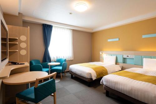 高知舒适高知酒店的酒店客房带两张床和一张桌子以及椅子。