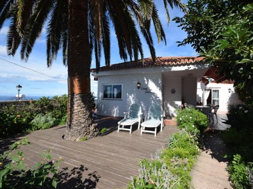 塔科龙特Cozy Holiday Home in Mesa del Mar with Sea View的一座房子,配有两把椅子和一棵棕榈树