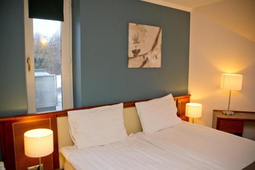 塔塔老湖高尔夫酒店的一间卧室配有一张带白色床单和两盏灯的床。