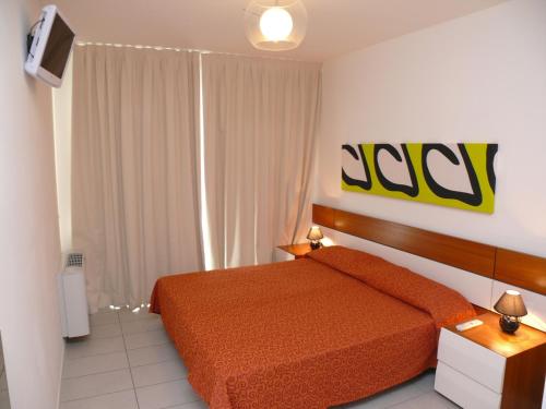 比比翁Residence Panorama Apart Hotel的一间卧室配有橙色的床和电视