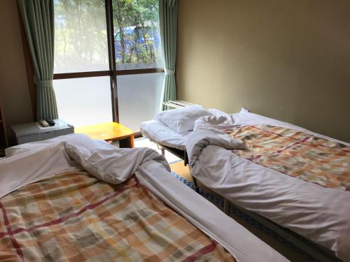 屋久岛和平民宿的带窗户的客房内设有两张单人床。
