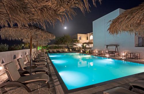 卡马利亚历山大酒店 的夜间游泳池,配有椅子和遮阳伞
